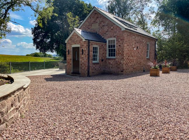 A brick house with planters in an outdoor area at Broadmoor Chapel Hereford