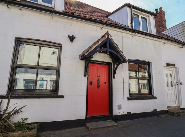 A house exterior with a red front door and windows at Fleming Cottage