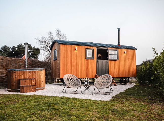 A wooden cabin with hot tub and chairs outside at Shepherds View in Bradley near Ashbourne