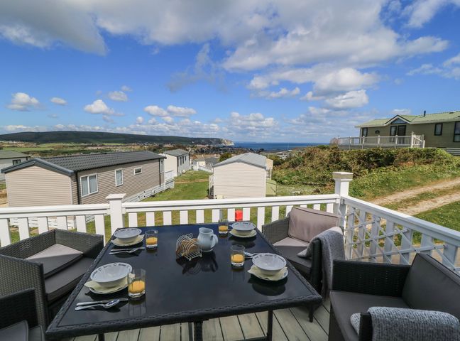 A patio area with a table and chairs overlooking the landscape at Swanny View in Swanage