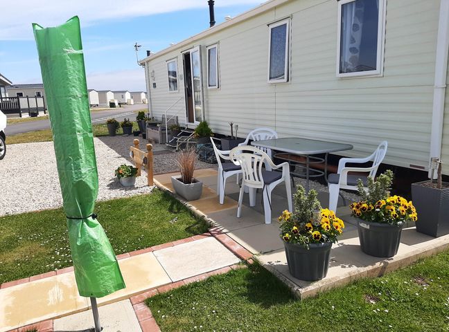 An outdoor area with a table, chairs, and flower planters at Taid's Retreat Silversands Cove beach lossiemouth