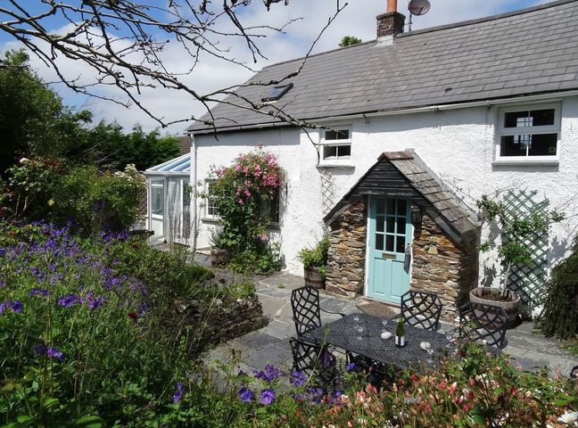 A cottage with a garden and a dining table at Mays Cottage in Wadebridge