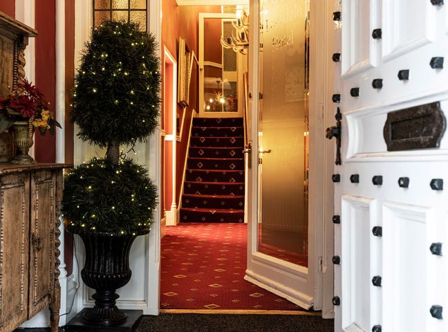 An entrance hall with a staircase and potted plants at Lonsdale House Bowness-On-Windermere