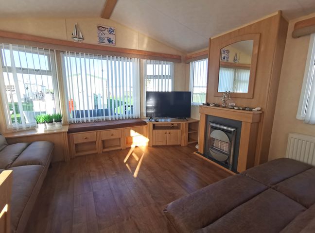 A living room with a television and sofa at Sea and Mountain view Sunbeach Holiday Snowdonia in Llwyngwril