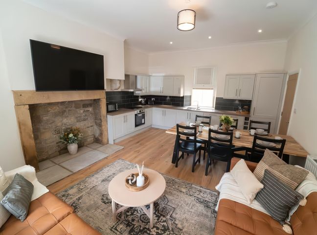 A living room and kitchen area with a television and dining table at Foundry Farm Apartment