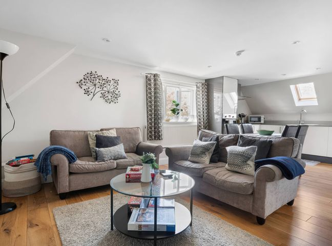A living room with sofas, a coffee table and kitchen units at TBC in 