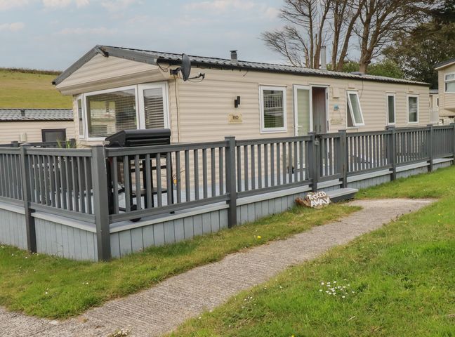 A caravan with decking and a fence at Tucked Away in Newquay