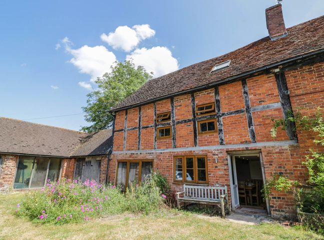 A house with a garden and bench at Netherend Barn in Colwall Green near Great Malvern