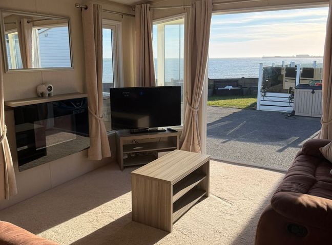 A living room with a sofa and a tv at Trecco Bay holiday park, Porthcawl