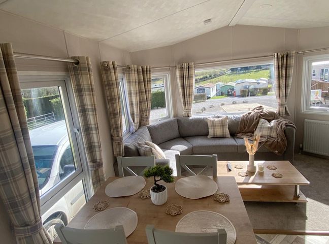 A living room with a sofa and table at a holiday home in an outdoor setting