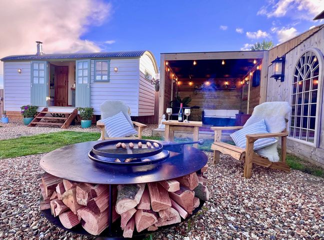 An outdoor area with a fire pit and seating at Olive Hut