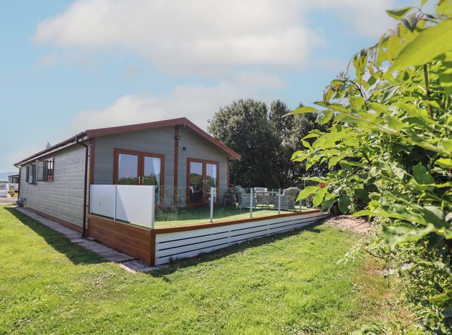 A house with a fenced area and grass at Excalabur 10 in Morfa Bychan