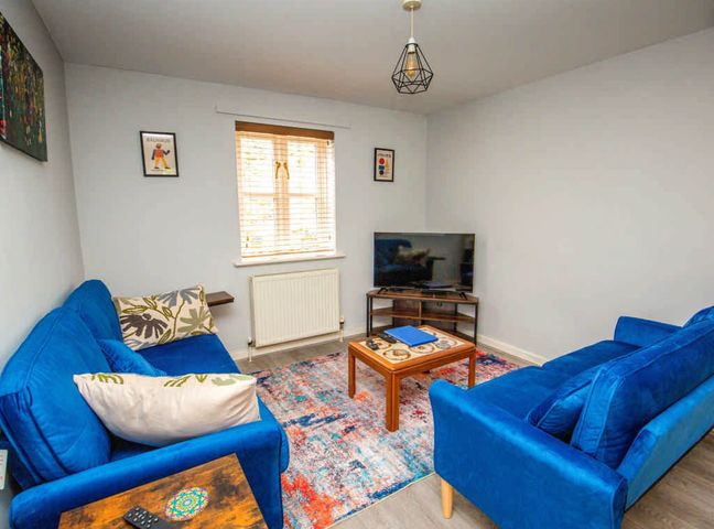 A living room with a TV and blue sofas at House Sleeps 4 with Parking and Garden in Glastonbury