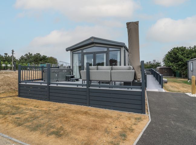 An outdoor area with a hot tub and grey sofa at Lodge 1 St. Osyth
