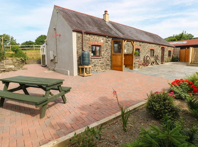 An outdoor area with a table and flowers at Coedllys Uchaf Cottage