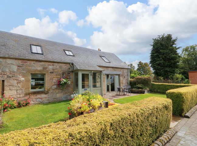 A garden view of a stone cottage with patio and flowerbed at Muirmailing Cottage Plean near Stirling