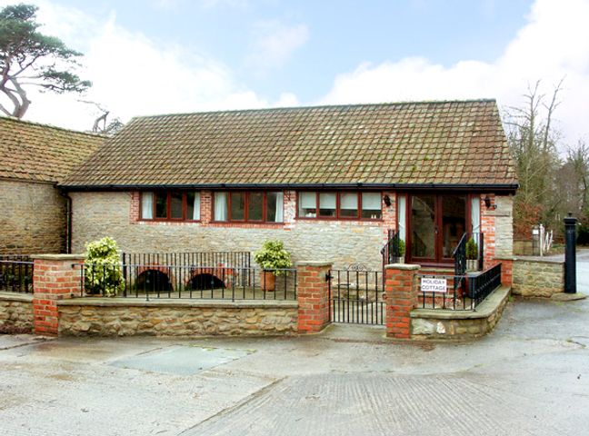 A stone and brick cottage with a tiled roof and metal railing at Brook Cottage in Milton on Stour near Gillingham