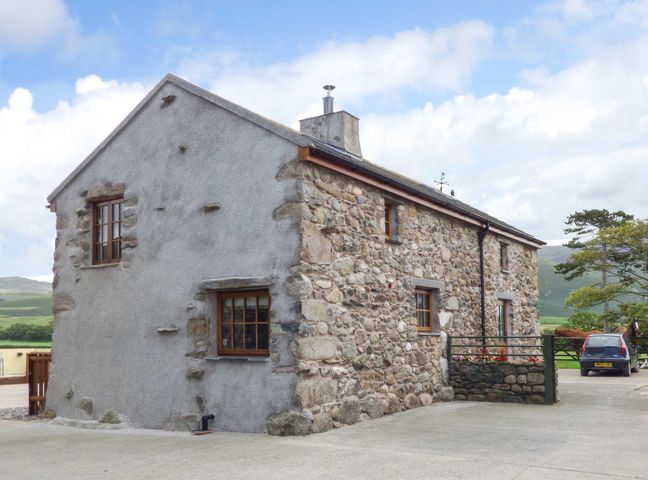 A stone and plaster cottage with wooden windows and a car parked nearby at Fell View Cottage in Bootle near Millom
