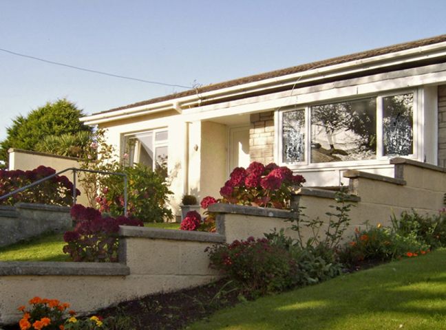 A single-story house with a front garden and flower beds at 1 Mirehouse Place in Angle near Pembroke
