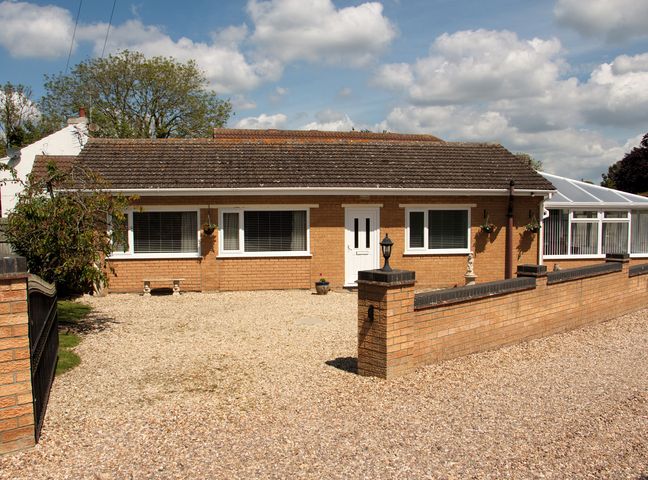 A bungalow with a front gravel driveway and brick wall at Long Acres in Old Leake near Boston