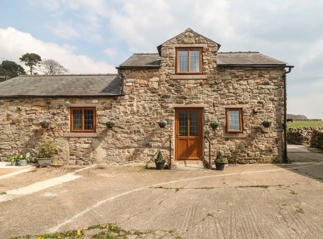 A stone house with wooden door and windows with plants in front at Fletchers Barn in Alderwasley near Wirksworth