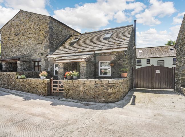 A stone cottage with flower pots on the wall and a wooden gate at Thimble Cottage in Pennington near Ulverston