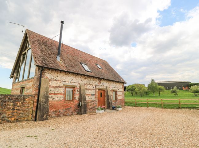 A barn style house with gravel driveway and green field at Shepherd's Barn Between Milborne St Andrew and Winterborne Whitechurch