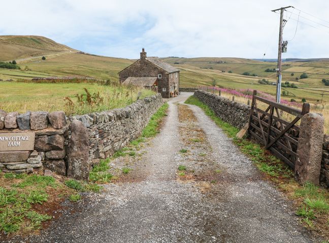 A gravel driveway leading to a stone house with stone walls and a wooden gate at New Cottage Farm in Quarnford and Flash near Buxton