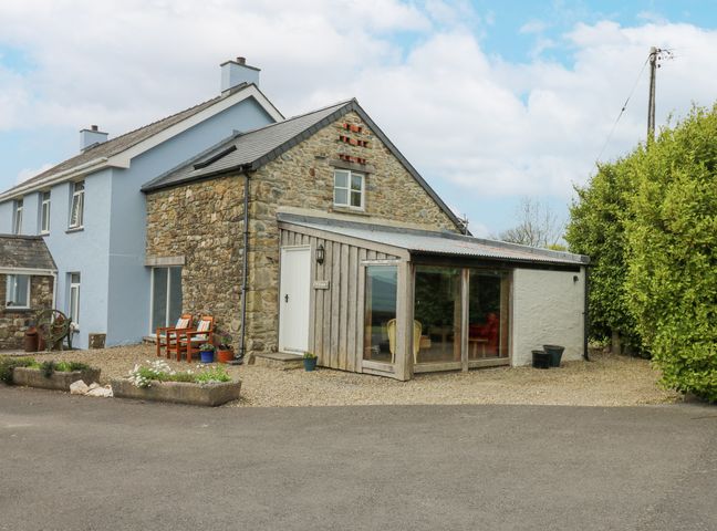A stone and blue house with a gravel area and chairs outside at Y Cwtch in Newport