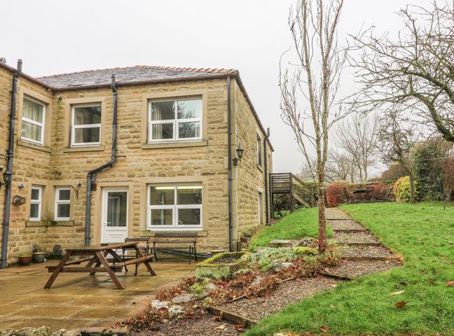 A stone house with a patio table bench and garden path at Laurel Bank Cottage in Embsay near Skipton