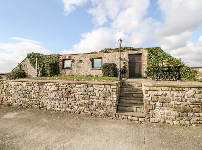 Stone building with two windows and a door with ivy and outdoor table and chairs at Cambridge Lodge in Wensley near Matlock