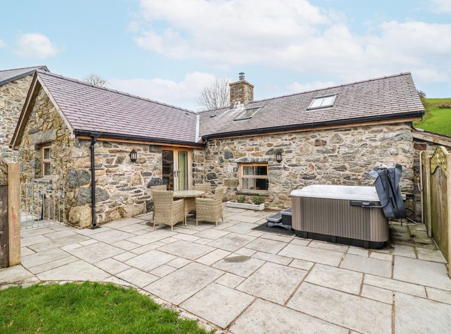 An outdoor seating area with a hot tub and dining furniture at Briws and 963354 together they sleep 35