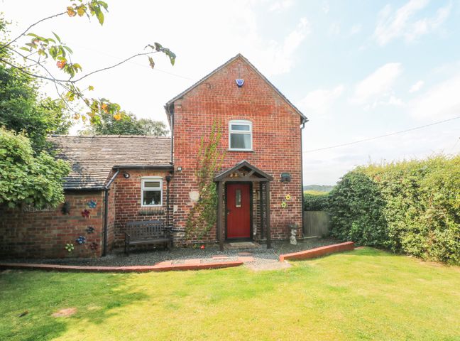 A brick house with a red door and a small porch in a garden at Top Stable Cottage Cross o'th' Hands near Turnditch