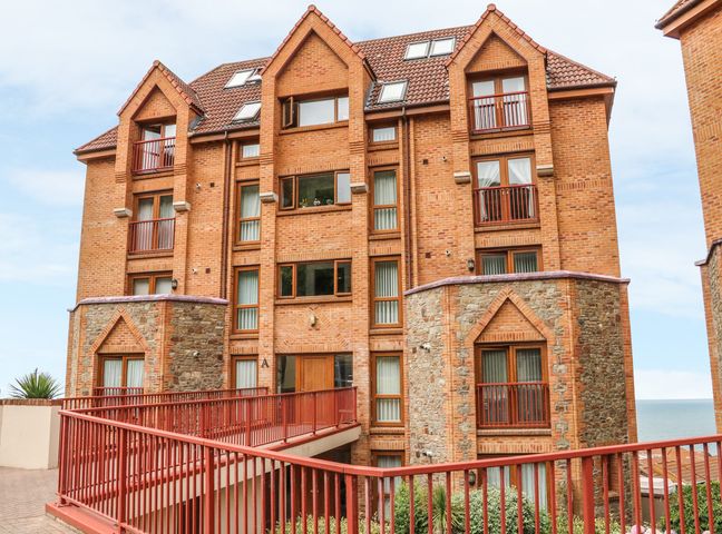 A multi-story brick apartment building with balconies and stone accents by the sea at 37 Ocean Park in Westward Ho