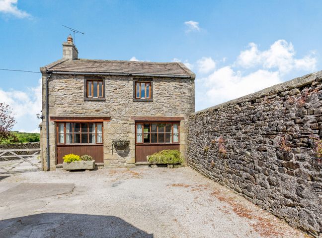 A stone cottage with two windows and a gravel driveway next to a stone wall at The Coach House in Giggleswick near Settle