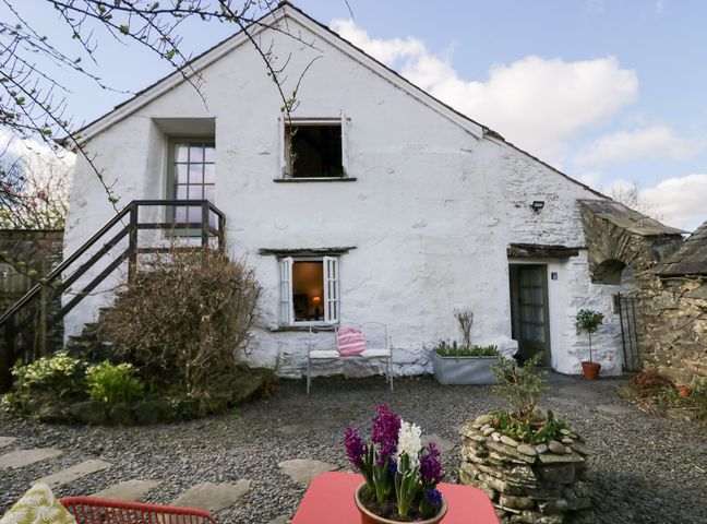 A courtyard with plants and outdoor seating in front of a white stone building at The Shippen Rusland near Crosslands