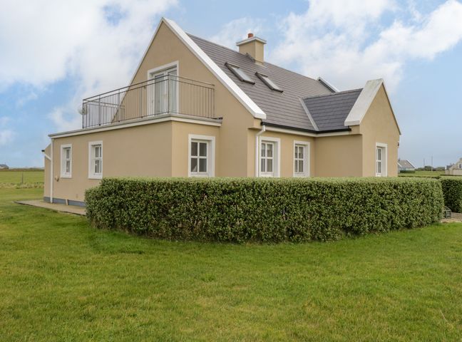 A beige two-story house with a hedge and grassy yard at 8 Lios Na Sioga in Binghamstown near Belmullet County Mayo