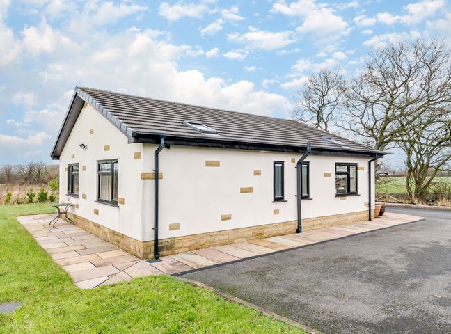The exterior of a single-story house with white walls and small stone accents at Sunnyside Shreyas Clayton Le Dale near Ribchester