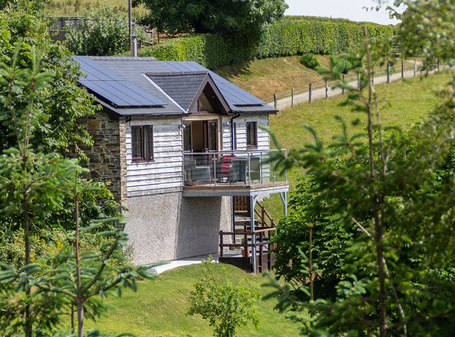 A small house with solar panels and a balcony on a grassy hillside at Black Mountain View in Llanafan Fawr near Builth Wells