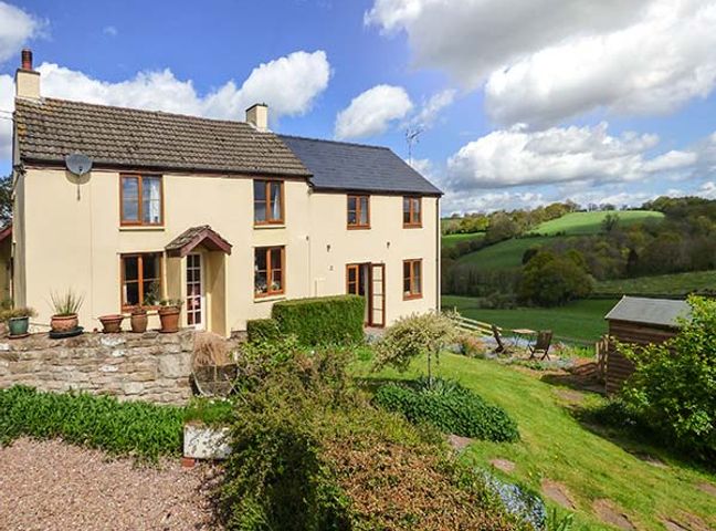 A countryside house with a garden and outdoor seating area overlooking green fields at Glebe Farm Cottage in Llandegveth near Cwmbran