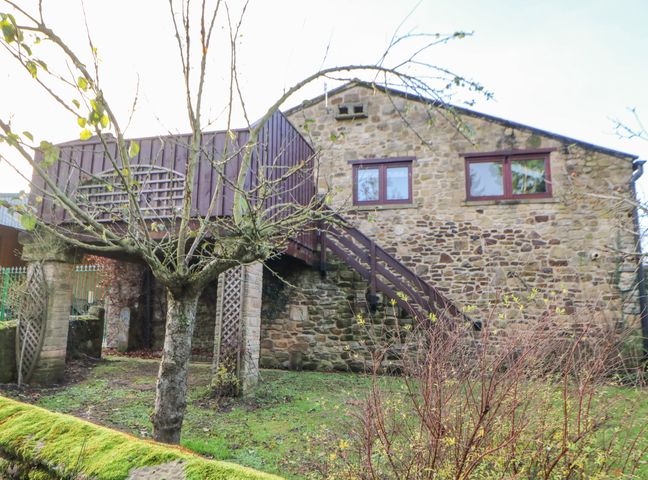 A stone building with wooden stairs and a balcony surrounded by trees and grass at Carvin-Tor Great Langton near Northallerton