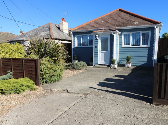 A blue single-story house with white trim and a concrete driveway at Smallcroft in Seasalter