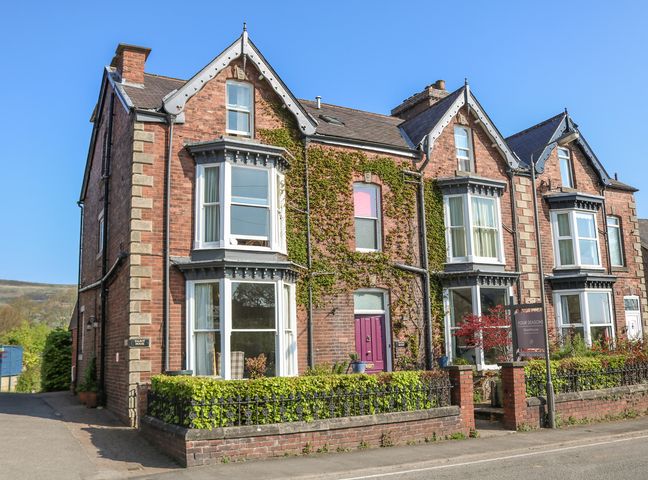 A red brick terraced house with bay windows and ivy on the facade at Talbot House Castleton Hope Valley