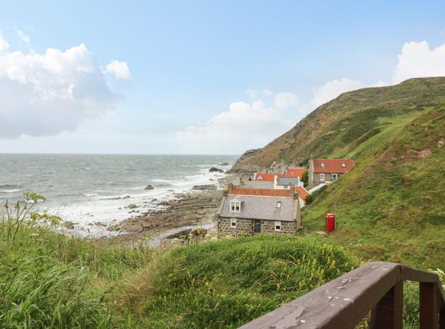 A coastal village with stone houses red roofs on a rocky shore near green hills at 49 Crovie Village Crovie near Gardenstown