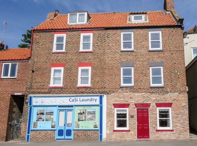 A brick building with CaSi Laundry shop and a red door house at Odd Sock Cottage in Whitby