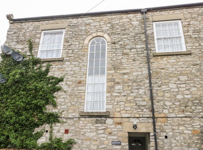 Stone building exterior with arched window ivy on wall and black door at Spire View in Pickering