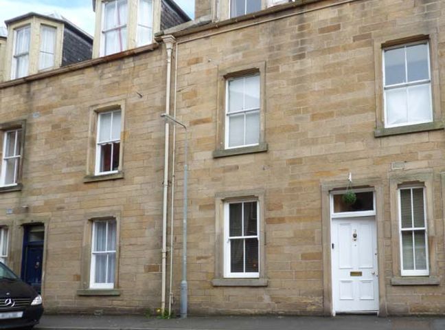 A street view of a stone building with white framed windows and a white door at 3 Queen Marys Buildings in Jedburgh near Kelso