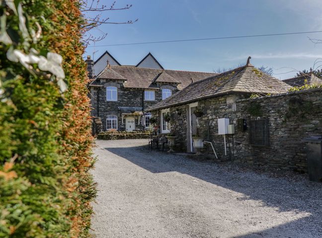 A stone house with a gravel driveway and a hedge on the left at Ees Wyke Studio in Sawrey