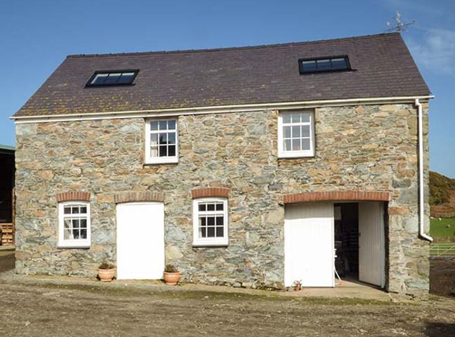 A stone exterior building with white doors and windows under a pitched roof at Bran Goesgoch in Holyhead