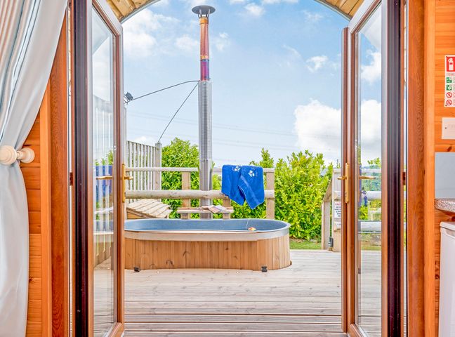 A wooden hot tub on a deck outside wooden double doors at Ewe Two in Oakenholt near Northop